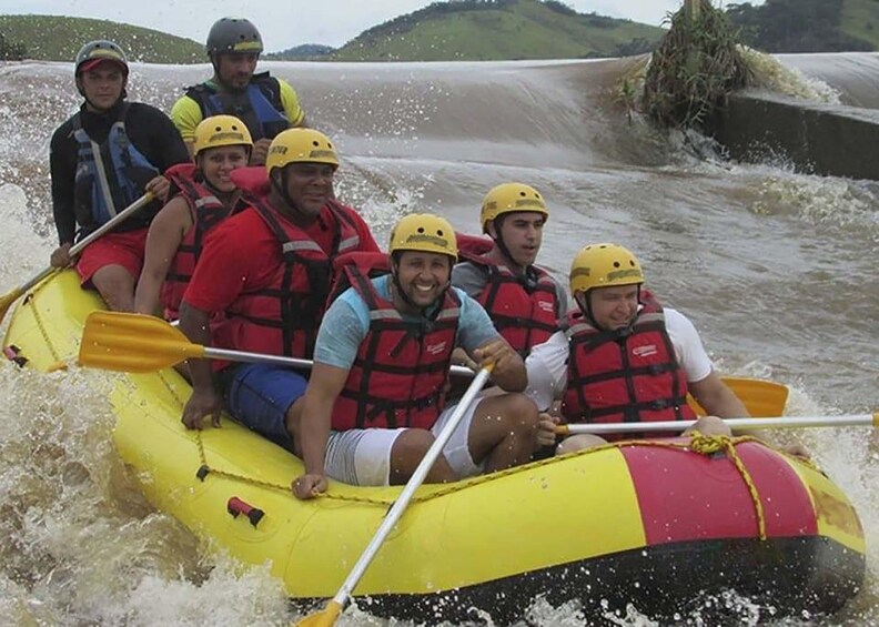 A group of people in a yellow raft with red and black life jackets, paddling through a river. 2