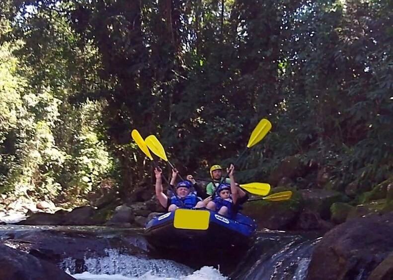 A group of people in a raft navigating a river with rapids, surrounded by dense forest. 3