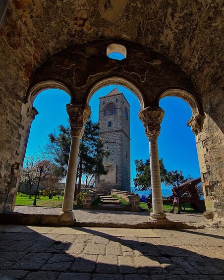 An ancient stone archway with a tower in the background. 3