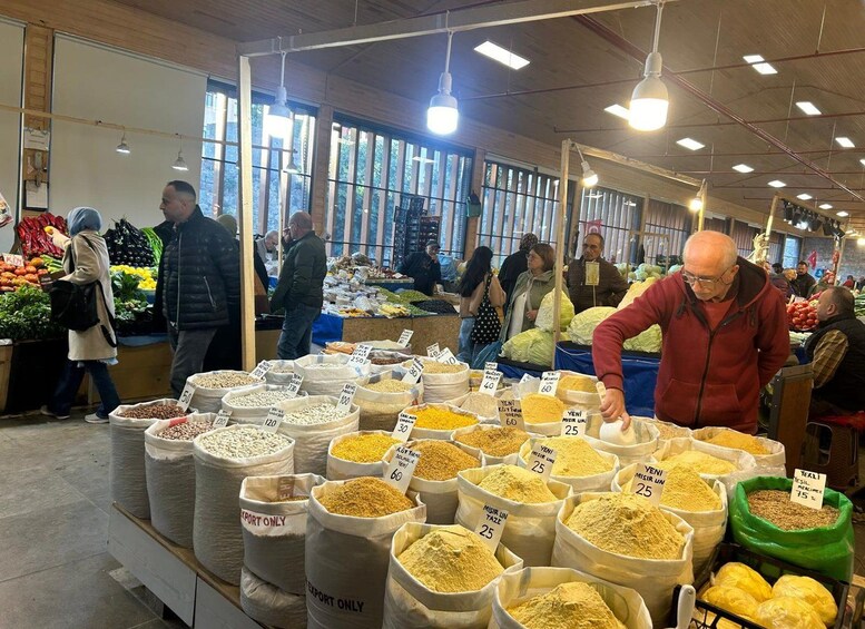 A bustling indoor market with various sacks of grains and vegetables on display. 2