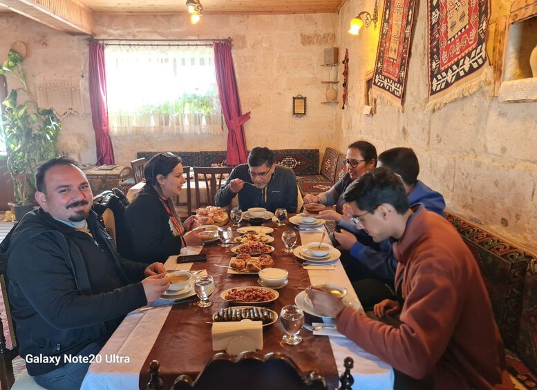 A group of people dining at a wooden table in a rustic setting with traditional decor. 2