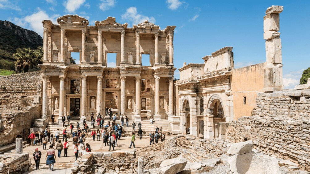 Ruinas antiguas con columnas y escalones, rodeadas de turistas. 4