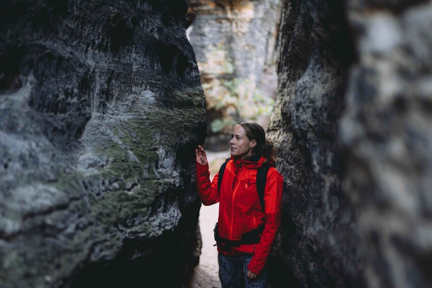 A person in a red jacket standing in a narrow rocky passageway. 2