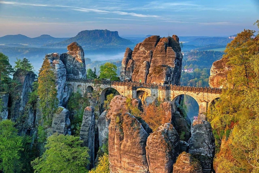 A stone bridge over a gorge with towering rock formations. 1