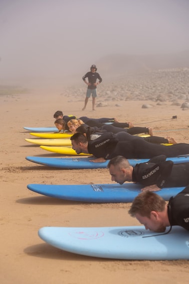 Un grupo de personas tiradas sobre tablas de surf en una playa. 1
