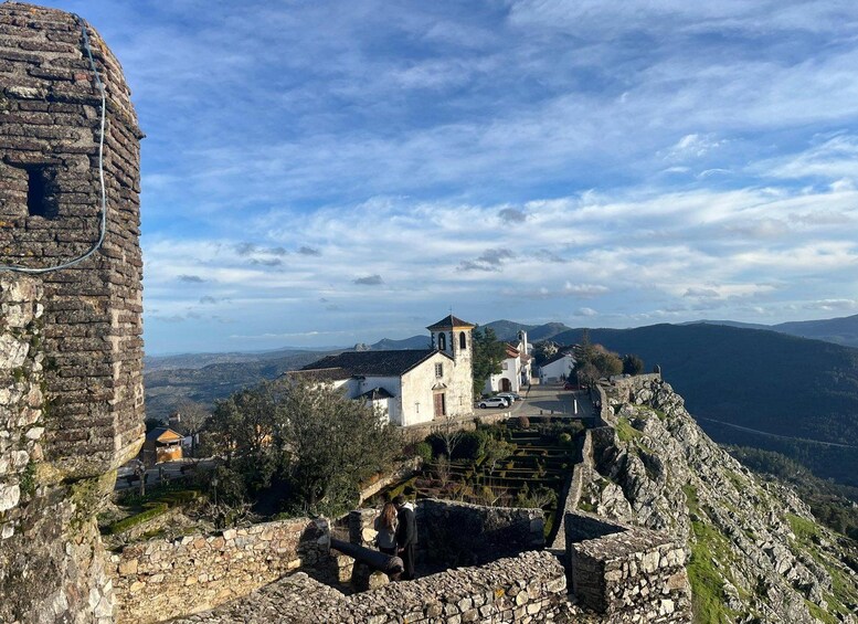 A historic stone wall, a church, and a mountainous landscape. 5
