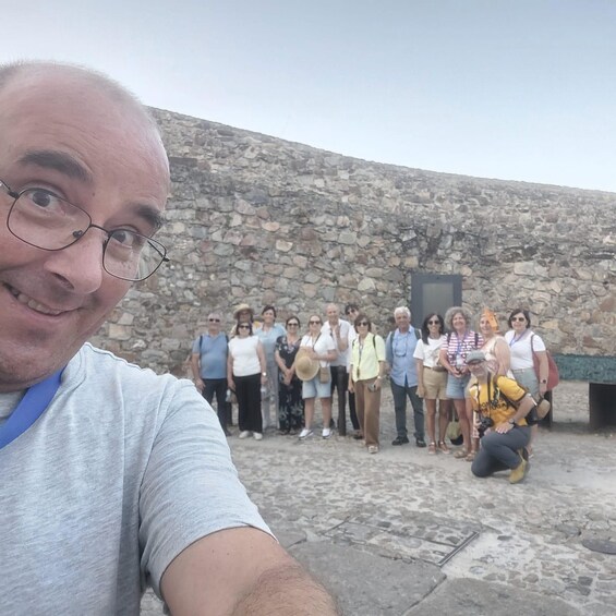A group of people standing in front of a stone wall with a metal door. 3
