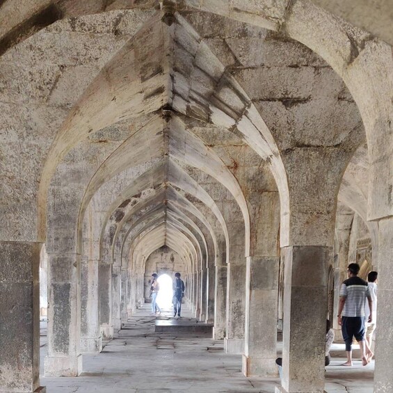 A long corridor with stone arches and columns, leading to a bright light at the end. 5