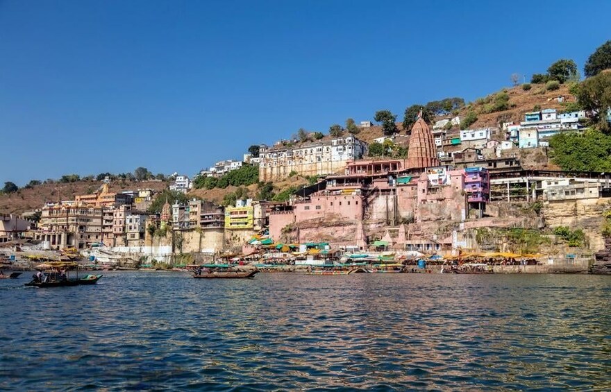 A riverside town with colorful buildings, a prominent temple, and boats on the water. 3
