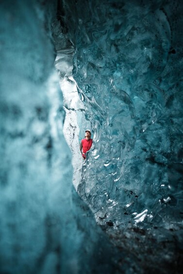 Una persona con camisa roja dentro de una cueva con formaciones de hielo. 4