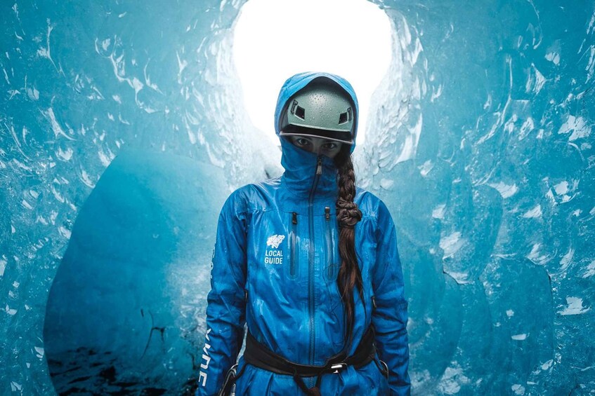 Una persona con chaqueta azul y casco, de pie en un túnel con paredes de hielo. 5