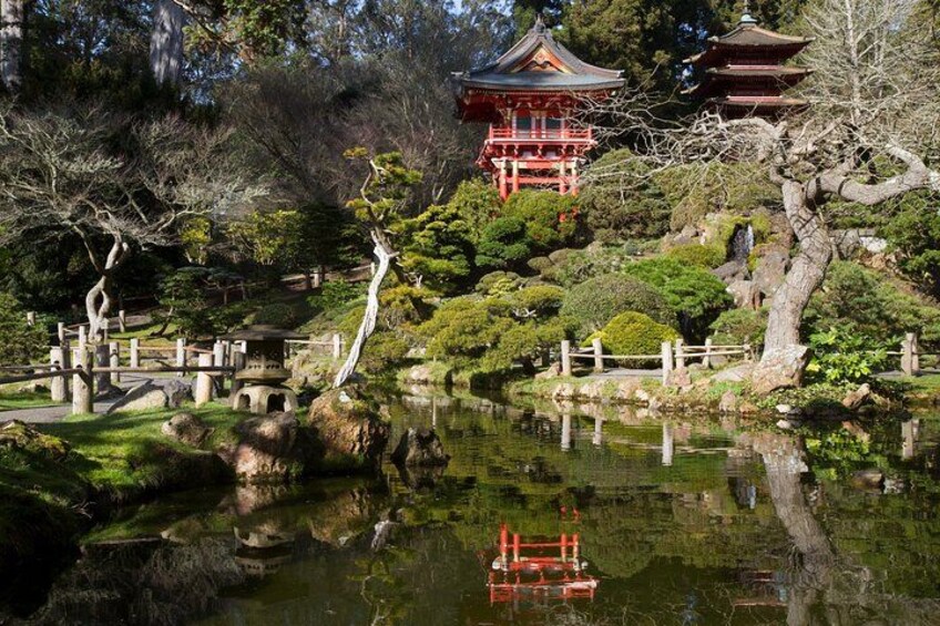 A traditional Japanese garden with a red pagoda, a pond, and various trees. 3