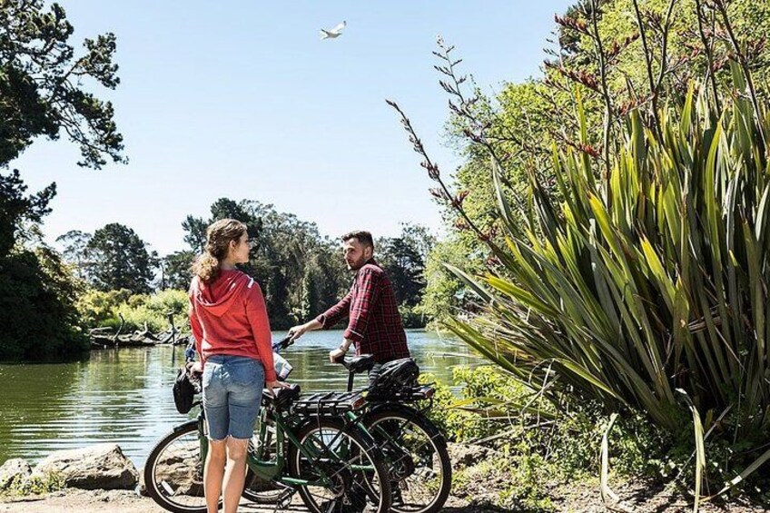Two people by a lake, one on a bicycle and the other standing. 5