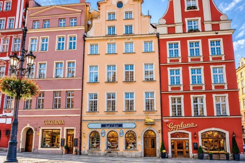 A row of colorful buildings with storefronts, including a shop named 'Goplana.' 2