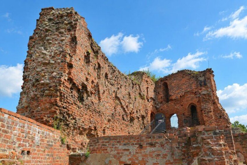 A historical brick structure with a tall tower and arched openings. 3