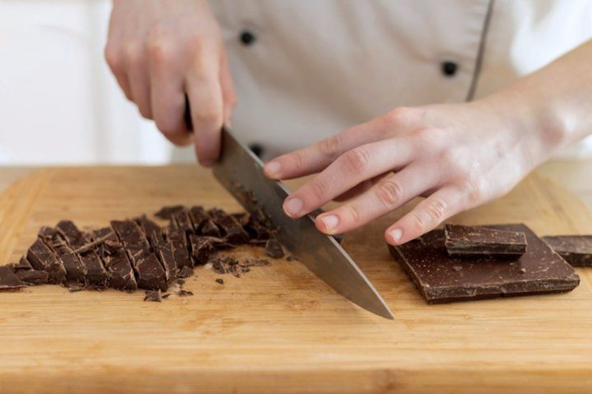 A person slicing chocolate on a wooden cutting board. 4