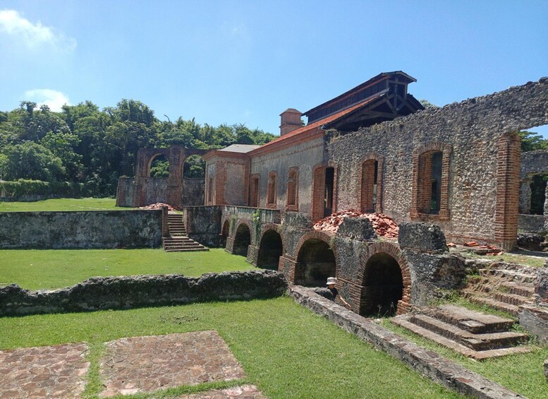 An ancient stone structure with arches and a staircase, surrounded by greenery. 1