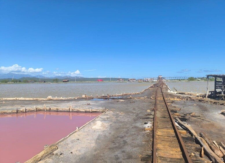 A railway track leading to a body of water with a small shed on the right. 2