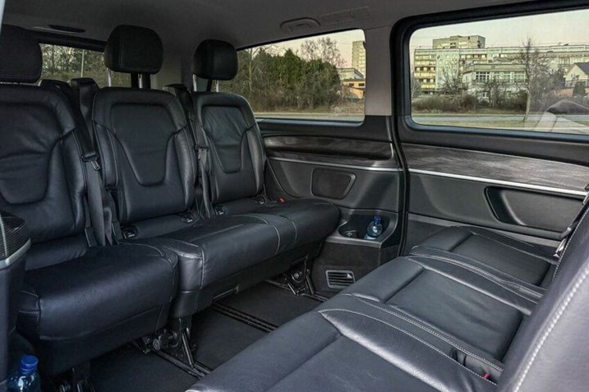 A vehicle's interior with black leather seats, a center console, and a rear view through the window. 2