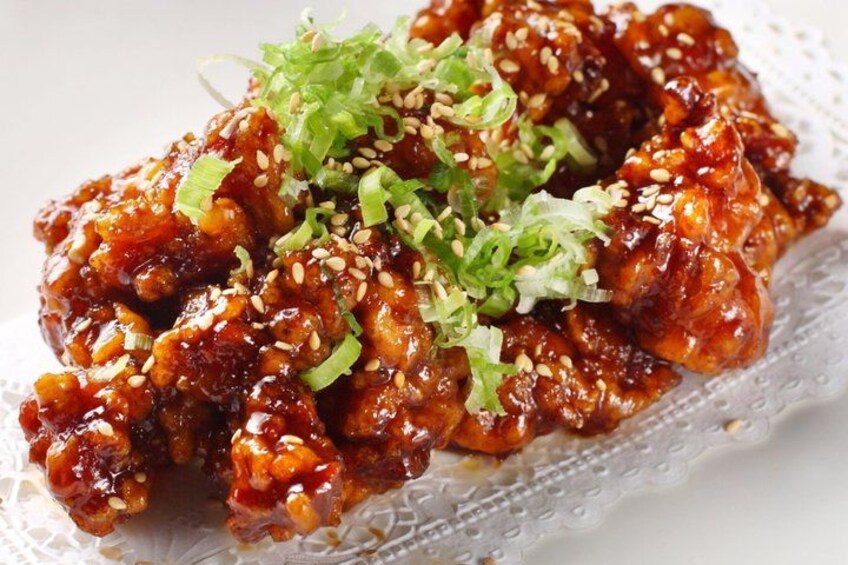 A dish of glazed chicken with sesame seeds and green onions. 4