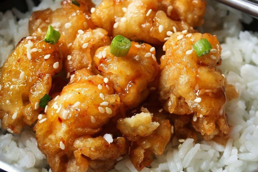 A dish of chicken wings with sesame seeds and green onions on top, served over white rice. 2