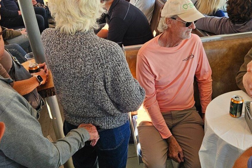 A person in a patterned sweater and a cap, seated at a table with a can of beer. 4