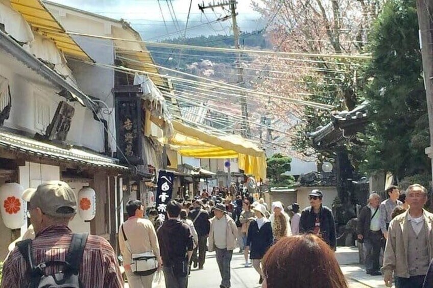 A crowded street with people walking, traditional buildings, and a yellow awning. 2