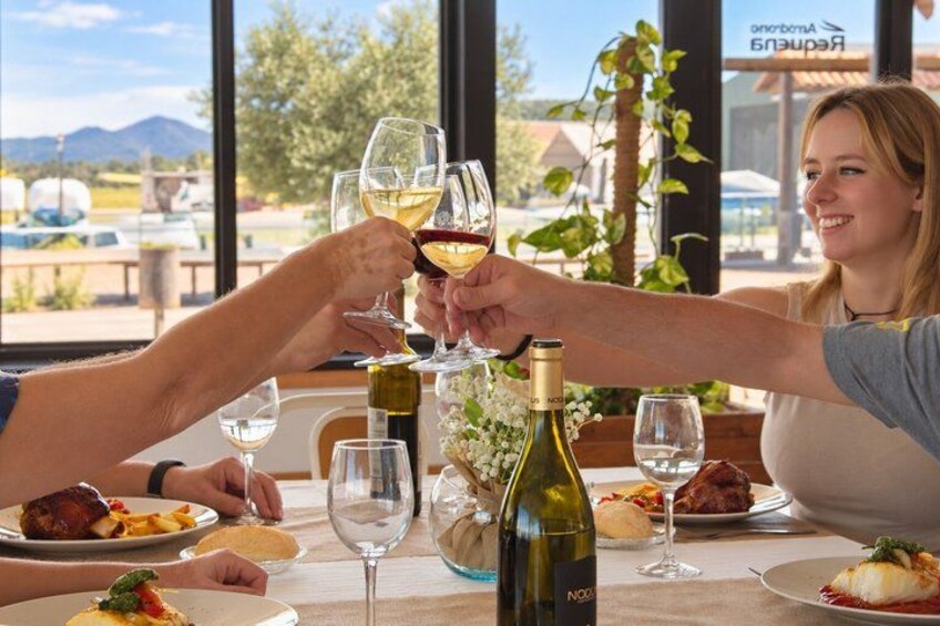 A dining table with wine glasses, a bottle of wine, and plates of food. 2