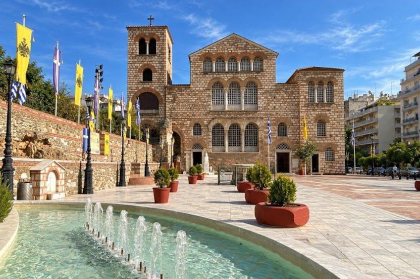 A historic building with a bell tower, a fountain, and multiple flags. 1