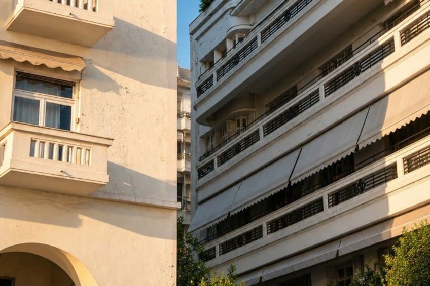 A multi-story building with balconies and a large arched doorway. 4