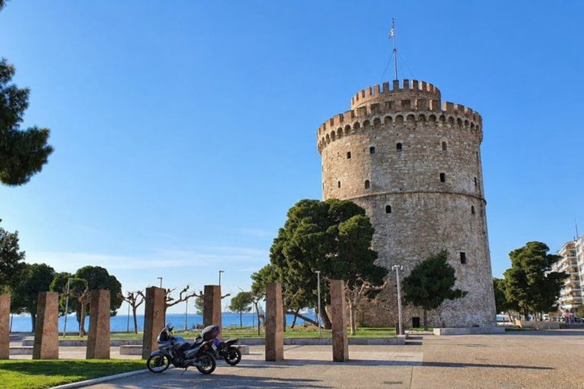 A historic stone tower with a flag, surrounded by trees and a clear sky. 2