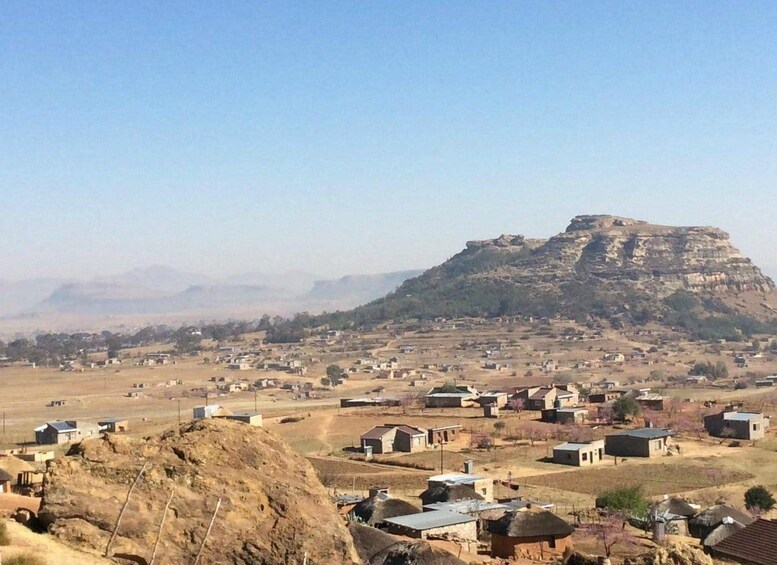 Un paisaje rural con casas dispersas, una colina destacada y un cielo despejado. 2