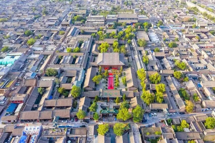 An aerial view of a densely packed urban area with traditional buildings, narrow streets, and a central red-roofed structure. 2