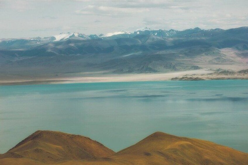 A mountain range with a lake in the foreground and snow-capped peaks in the background. 3