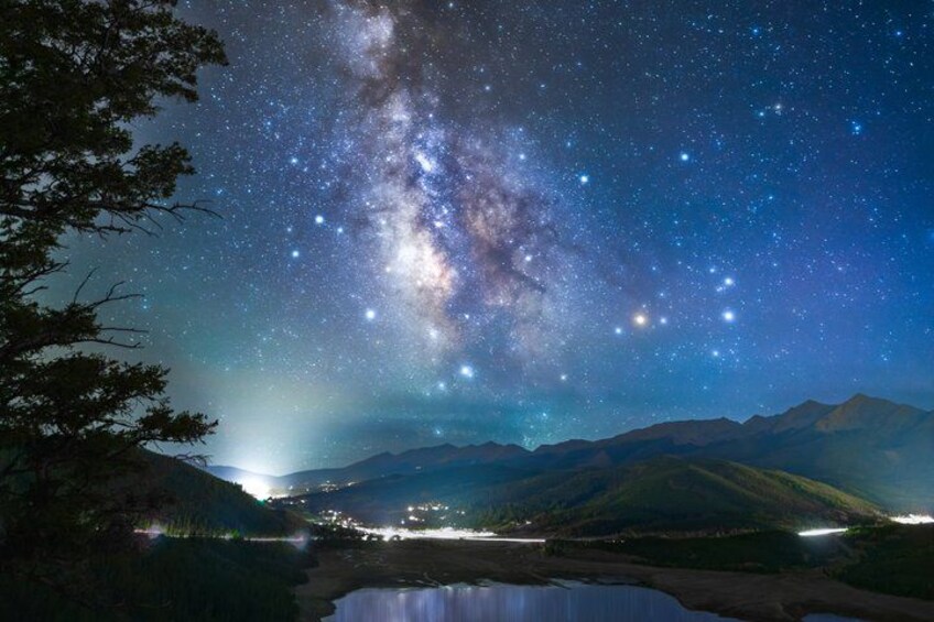 A night sky with stars and the Milky Way, a mountain range, and a lake. 1