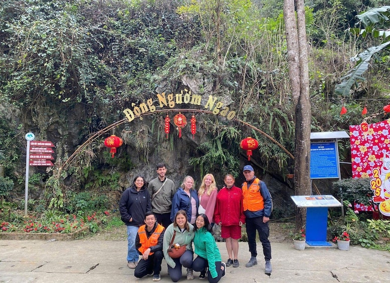 Eine Gruppe von Personen posiert vor einem Schild mit der Aufschrift 'Dong Nguyen Ngao', mit roten Laternen und einer blauen Informationstafel. 4