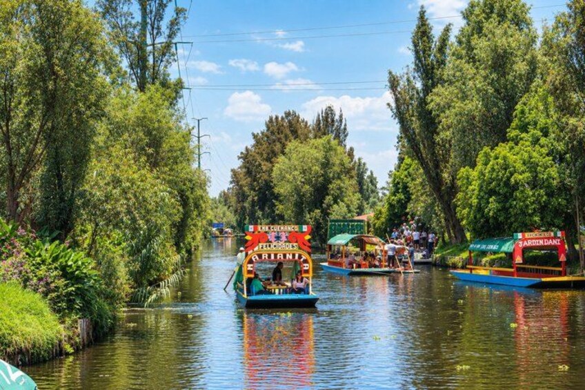 A canal with boats, trees, and a clear sky. 4