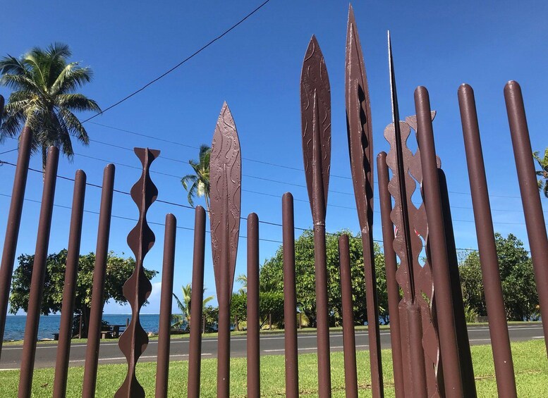 A metal sculpture with abstract shapes and a palm tree in the background. 2