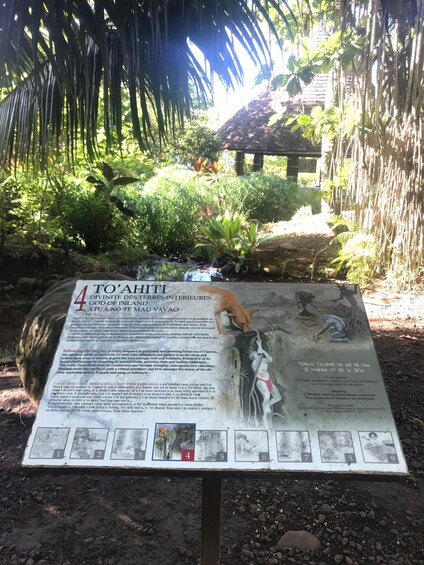 A sign with information about To'ahiti, a god of inland waters, surrounded by lush greenery and a small waterfall. 4