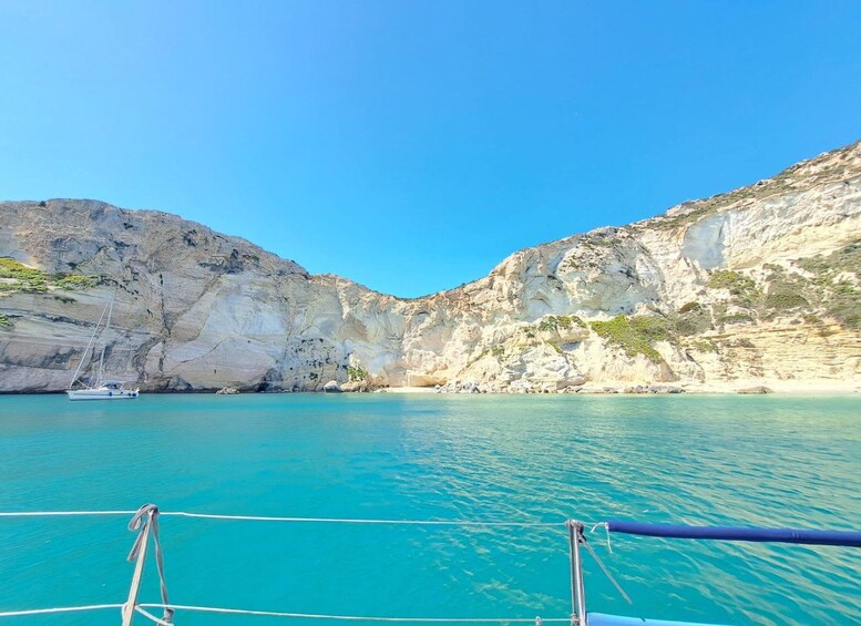 A boat on turquoise water with rocky cliffs and a clear sky. 5