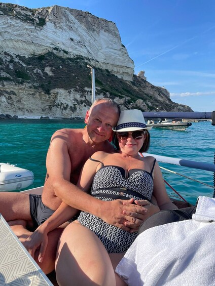 A couple on a boat with a rocky cliff in the background. 2