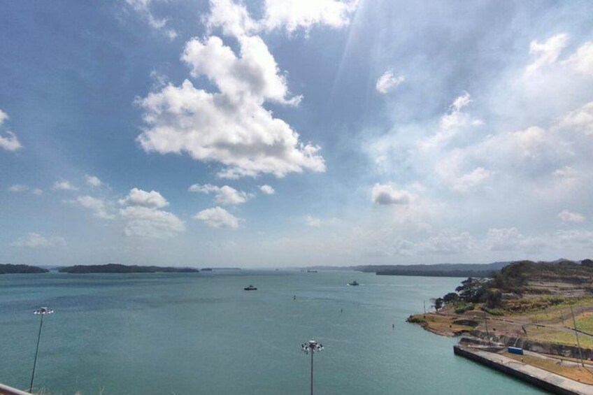 A coastal landscape with calm waters, a pier, and distant islands. 2