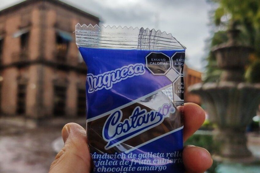 A hand holding a chocolate bar with a blue and white label. 3