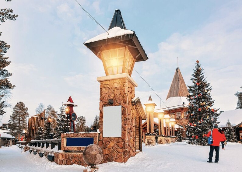 Un chalet enneigé, avec une entrée en pierre, une lanterne illuminée et un sapin de Noël décoré. 5