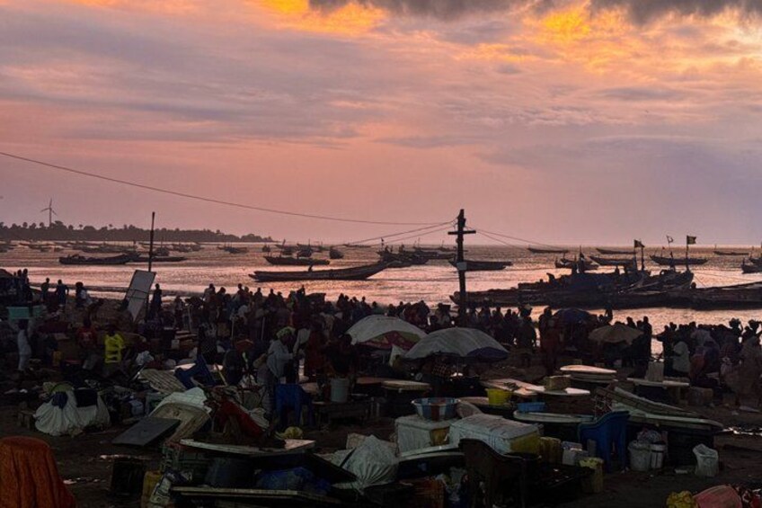 A crowded riverside market with boats and people. 1