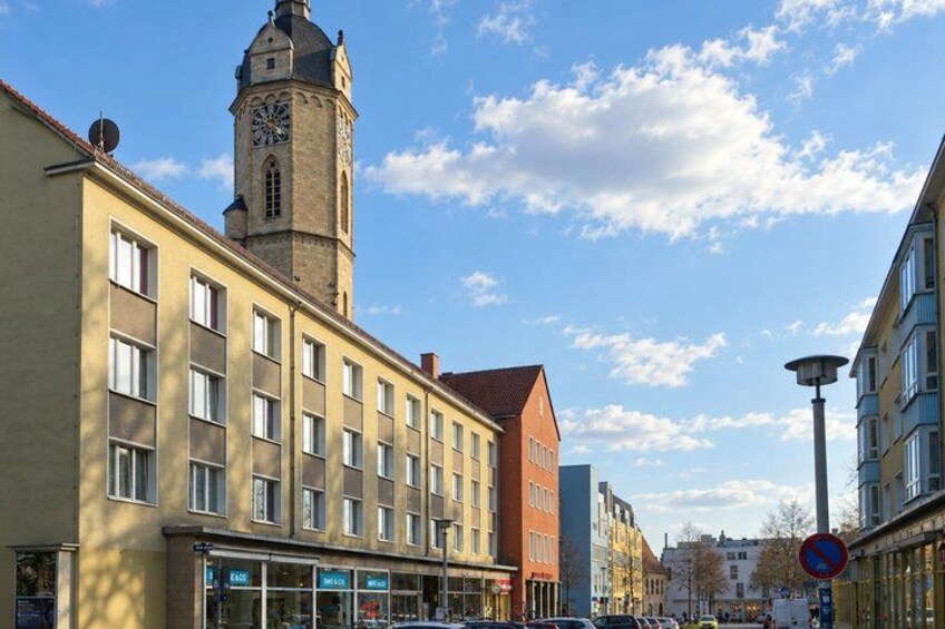 A street with buildings, a clock tower, and a clear sky. 5