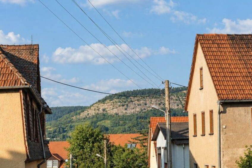 A village with red-tiled roofs, a hill in the background, and power lines. 3