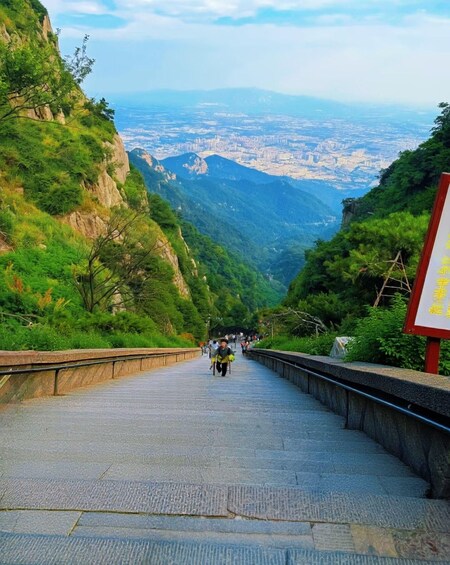 A steep mountain road with a view of a city in the distance. 3