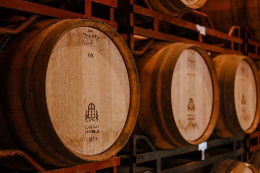 Wooden barrels with labels, arranged on shelves in a storage area. 4