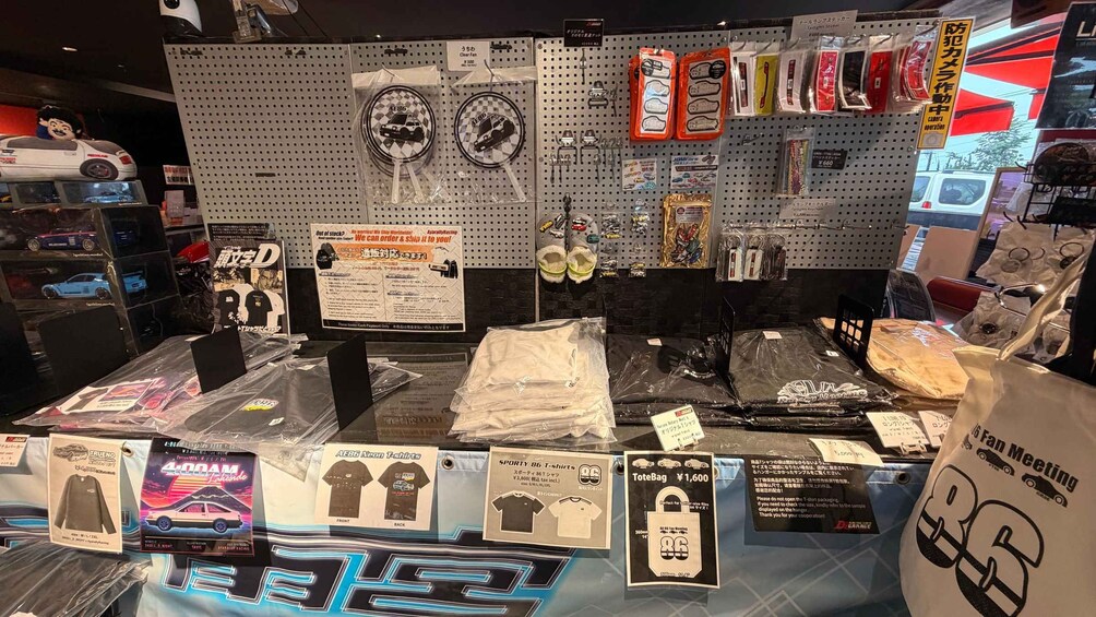 A display of merchandise including t-shirts, keychains, and other items with racing car themes. 5